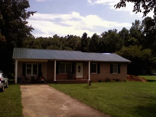 Dark green metal roof on a brick ranch with a covered porch in Bassett